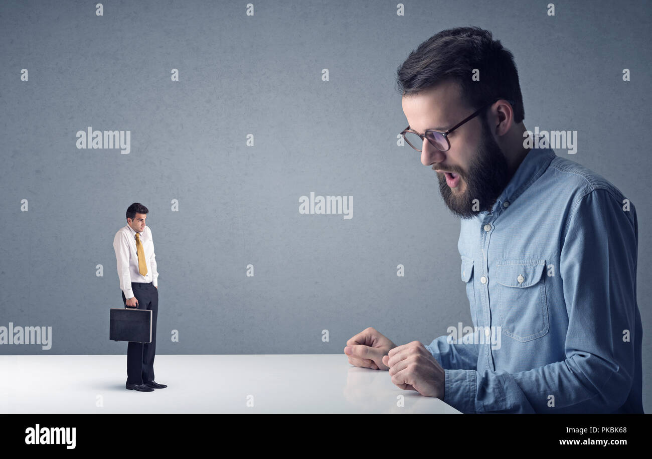 Giovane imprenditore professionale essendo arrabbiato con un altro imprenditore in miniatura Foto Stock