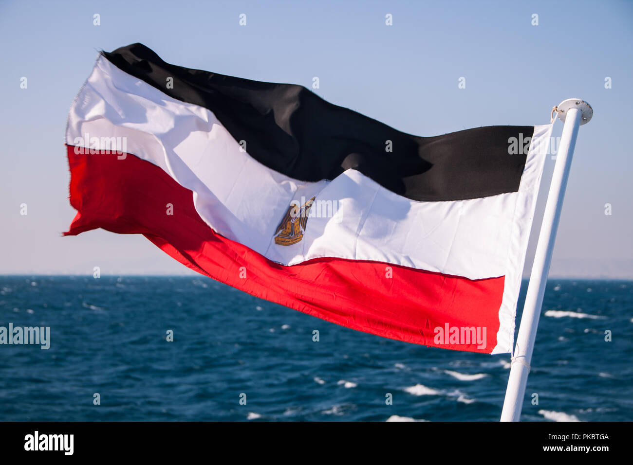 Bandiera egiziana in flottante il sole con mare rosso in background Foto Stock