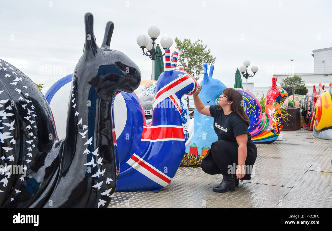Brighton Regno Unito 12 Settembre 2018 - Kayla Fuller dà la lumaca sculture una cancellazione rapida al lancio dell'arte Snailspace Trail sul molo di Brighton oggi . Cinquanta decorate le lumache giganti e sessanta junior va a passo di lumaca sculture dipinte da artisti locali in collaborazione con Wild in arte saranno presenti intorno alla città di Brighton e Hove tra il XV Settembre fino al 18 novembre. Essi sono sponsorizzati da imprese locali e finirà per essere messo all'asta per raccogliere fondi per l'Ospizio Martlets Credito: Simon Dack/Alamy Live News Foto Stock