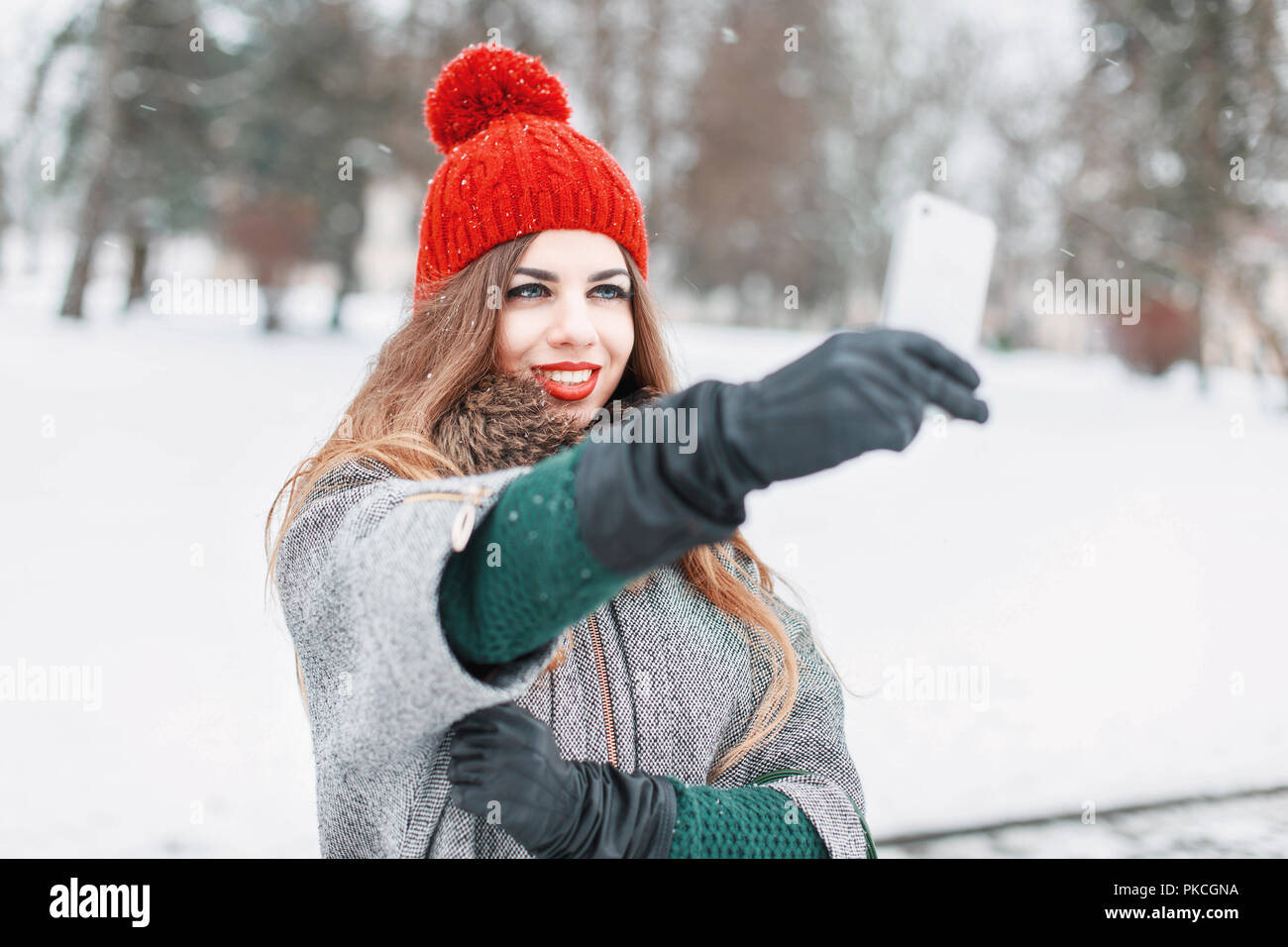 Tempo Selfie. Gioiosa di giovani donne rendendo selfie dal suo smart phone. Inverno nevoso giorno. All'esterno. Foto Stock