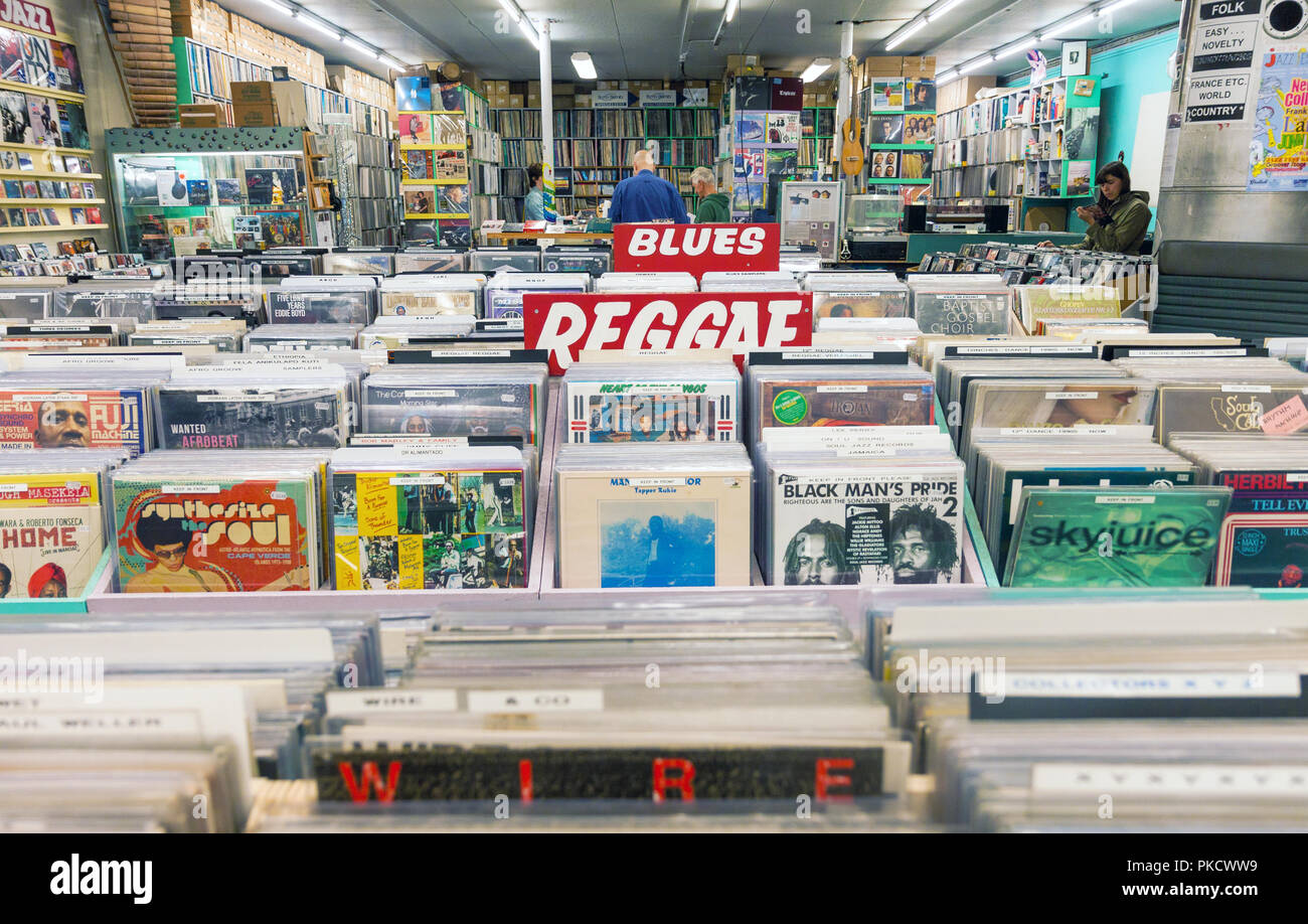 Il vecchio record di musica shop interno con cremagliere piena di vinile vintage record girevole e i clienti che vagano. Foto Stock