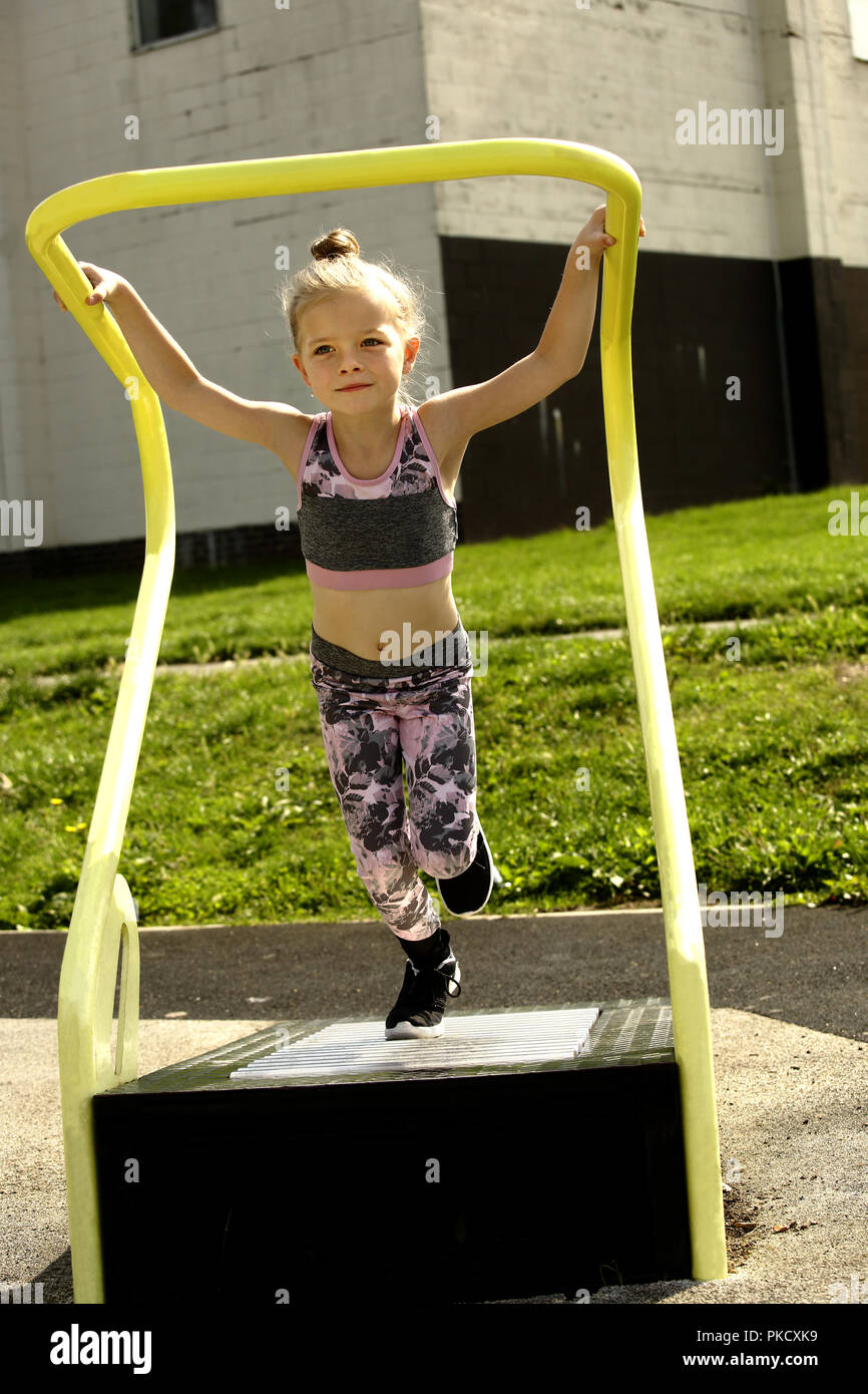 6 anno vecchia ragazza, su una macchina da corsa in un libero per uso esterno area fitness Foto Stock
