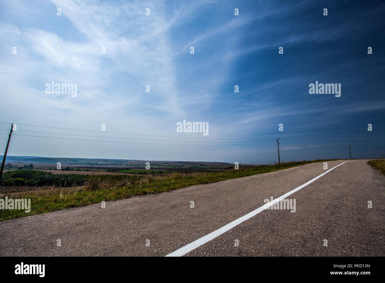Svuotare strada asfaltata e cielo blu con nuvole bianche Foto Stock