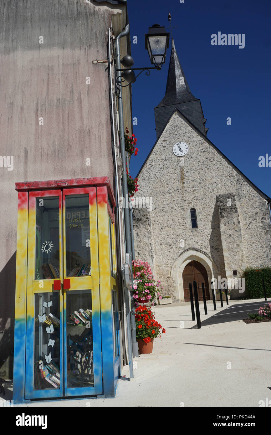 Colorato phone booth trasformato in una piccola biblioteca di libri usati per la lettura e lo scambio da parte della chiesa in un piccolo villaggio della Francia Foto Stock