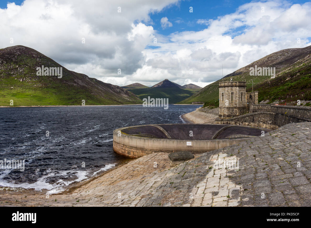 Silent Valley il serbatoio di troppopieno tonda in primo piano e la vista da Doan montagna nella Mourne Mountains. SIlent Valley, vicino Kilkeel, County Dow Foto Stock