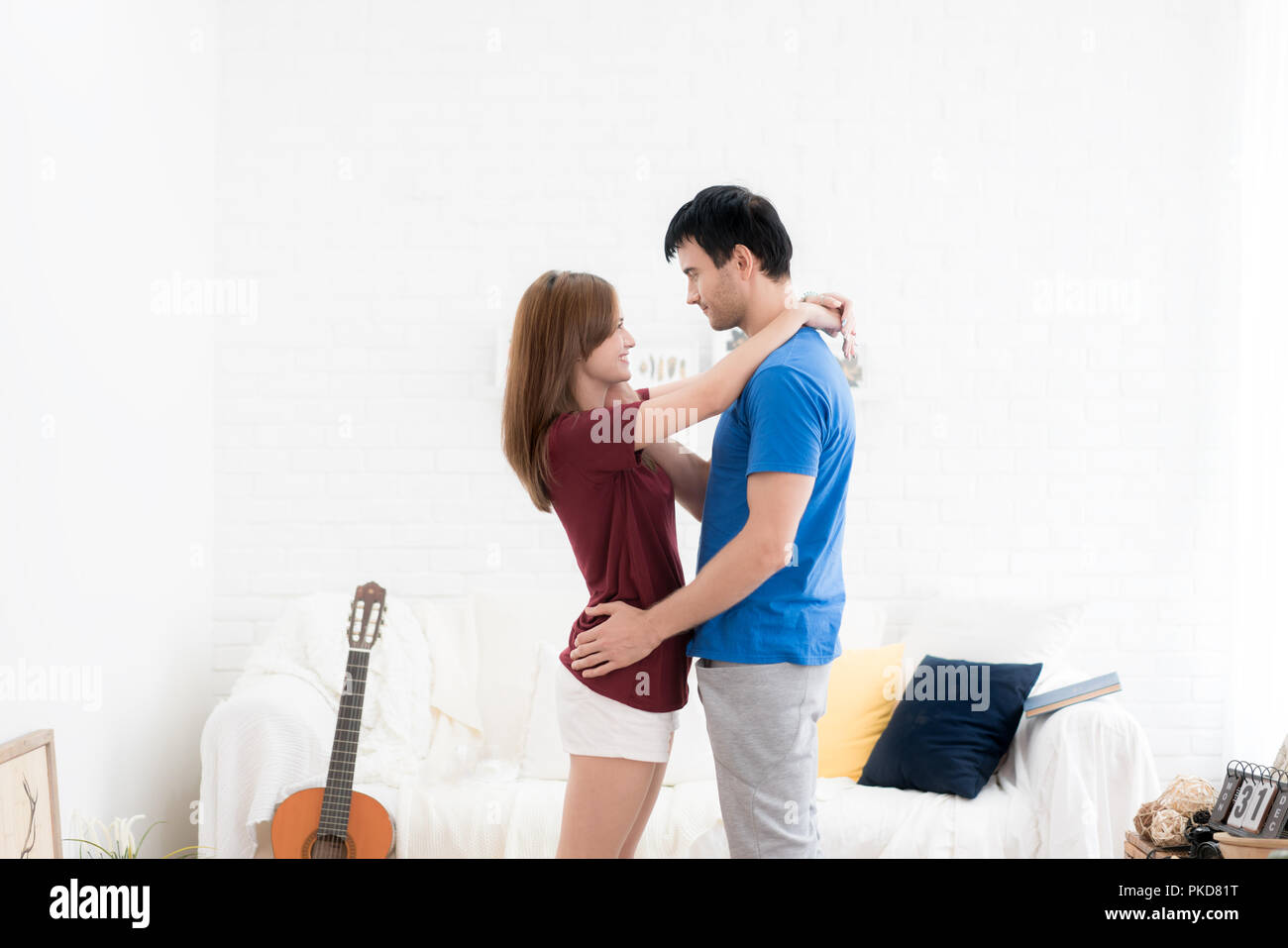 Giovane bella asiatica matura in piedi nel salotto di casa, Sorriso Uomo asiatico e gli amanti della donna abbraccio insieme. Foto Stock