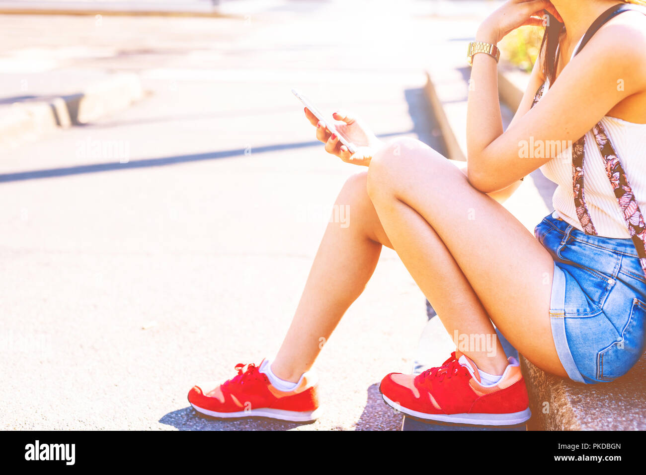 Middlesection giovane donna utilizzando smart phone outdoor luce posteriore - streaming, tecnologia, internet concept Foto Stock