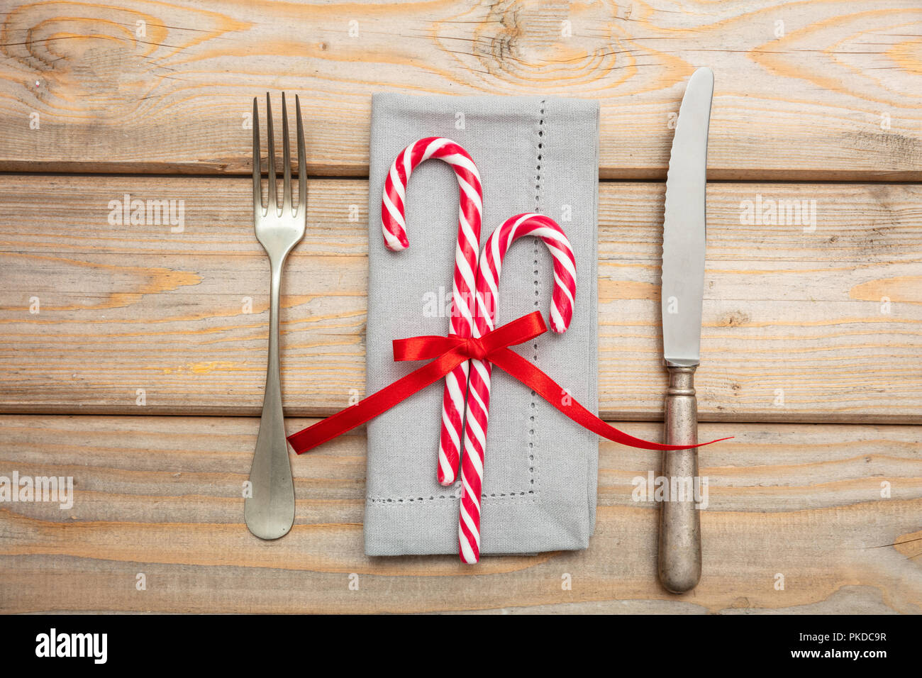 Tavola di natale l'impostazione. Posate e candy canes su grigio igienico, sullo sfondo di legno, vista dall'alto Foto Stock