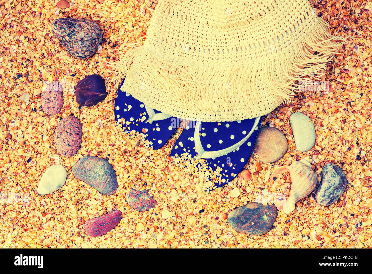 Scena di spiaggia. Sun cappello di paglia e flip-flop sandali giacente sul mare coquina conchiglie sulla spiaggia Foto Stock