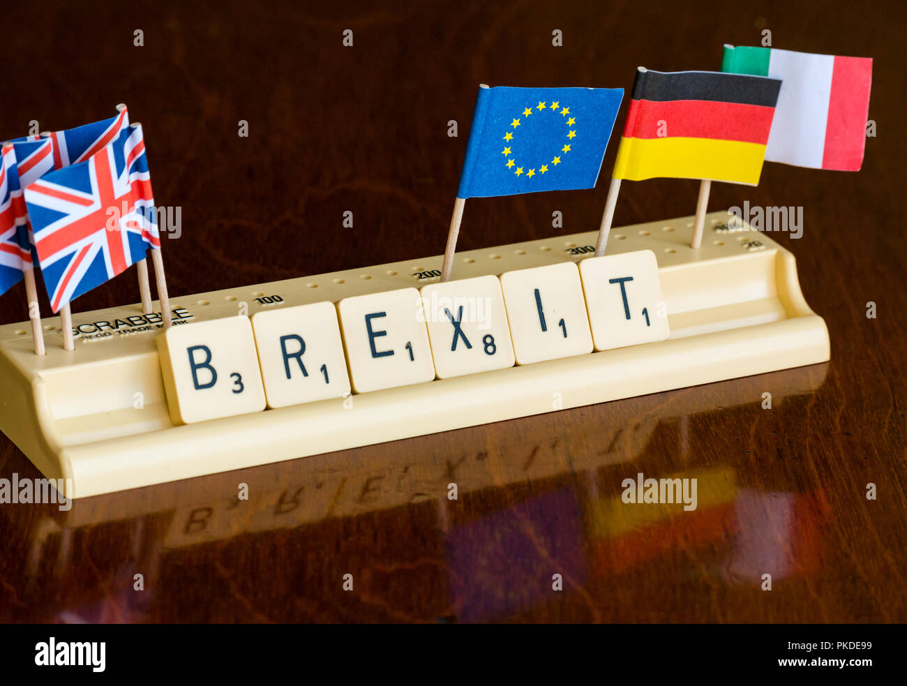 Lettere di Scrabble Brexit ortografia nel vassoio di Scrabble con britannica Union Jack e bandiera UE su mogano scuro dello sfondo Foto Stock