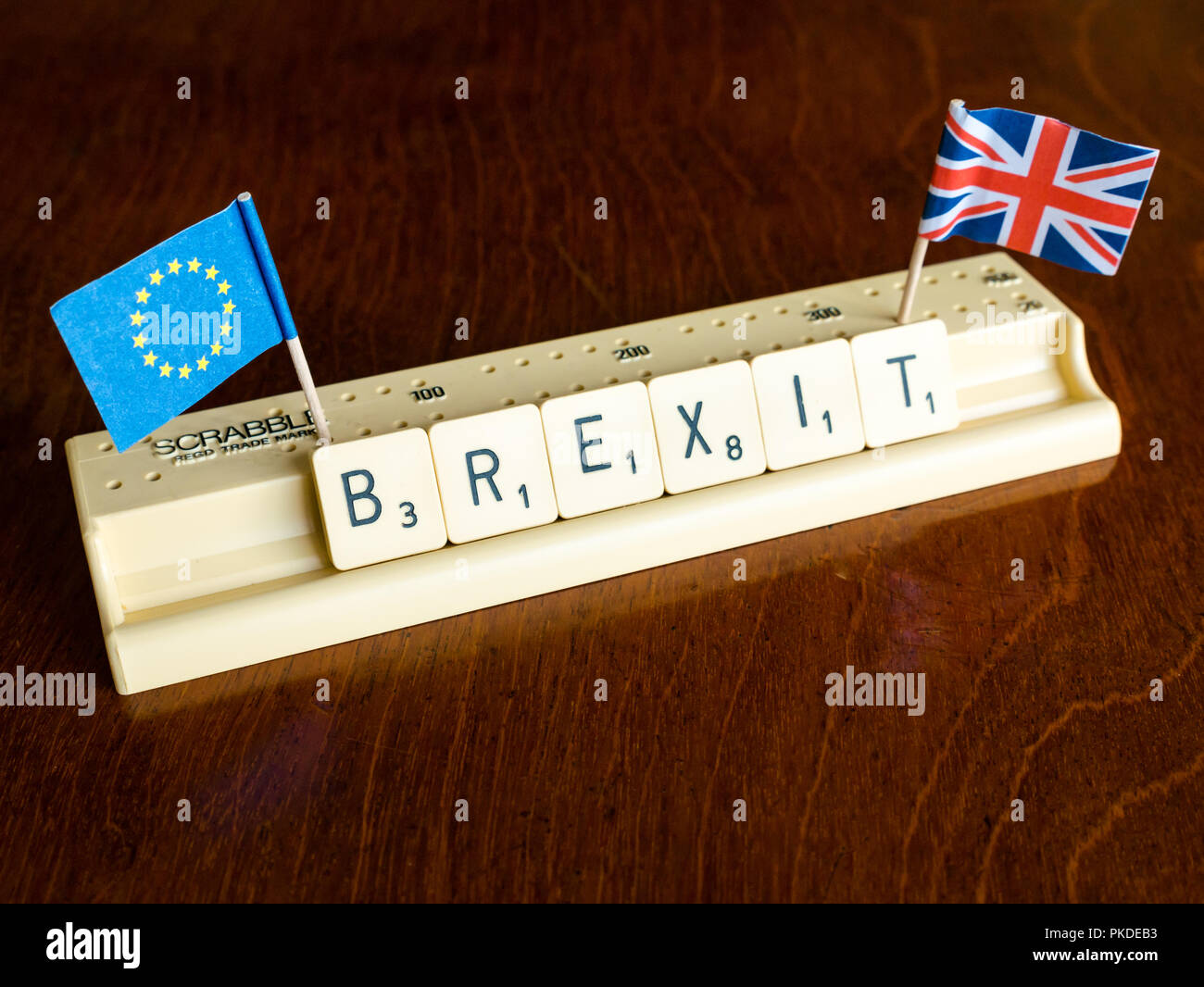 Lettere di Scrabble Brexit ortografia nel vassoio di Scrabble con britannica Union Jack e bandiera UE su mogano scuro dello sfondo Foto Stock