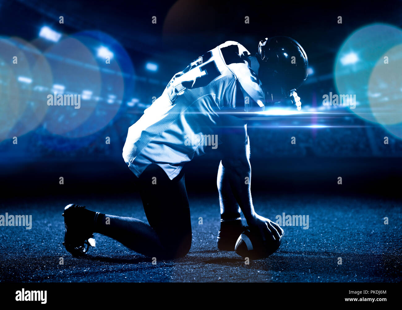 Giocatore di football americano a partire del gioco del calcio americano sul campo di calcio di notte Foto Stock