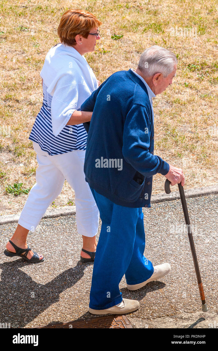 Donna Uomo aiutando con bastone lungo il marciapiede - Francia. Foto Stock