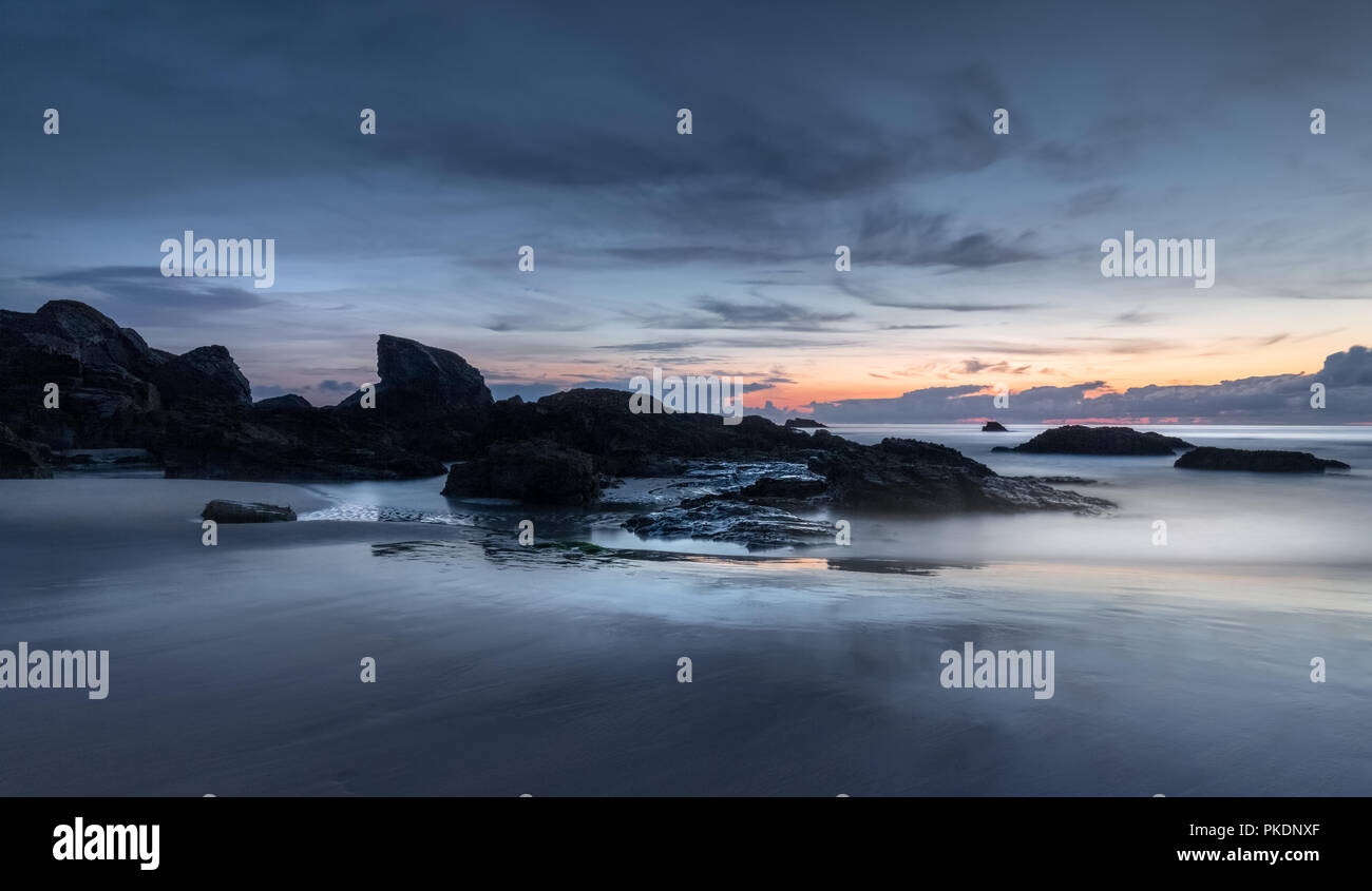 Orizzonte Glow, oltre stagliano rocce, Porthcotham Beach, Cornwall Foto Stock