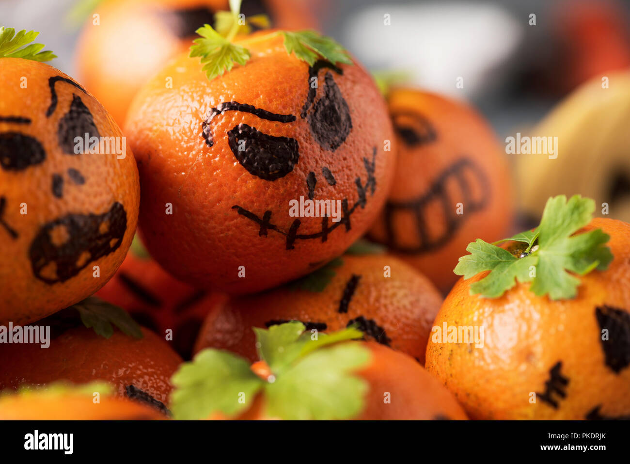 Primo piano di alcuni tangerini allestito come zucche intagliate con facce buffe Foto Stock