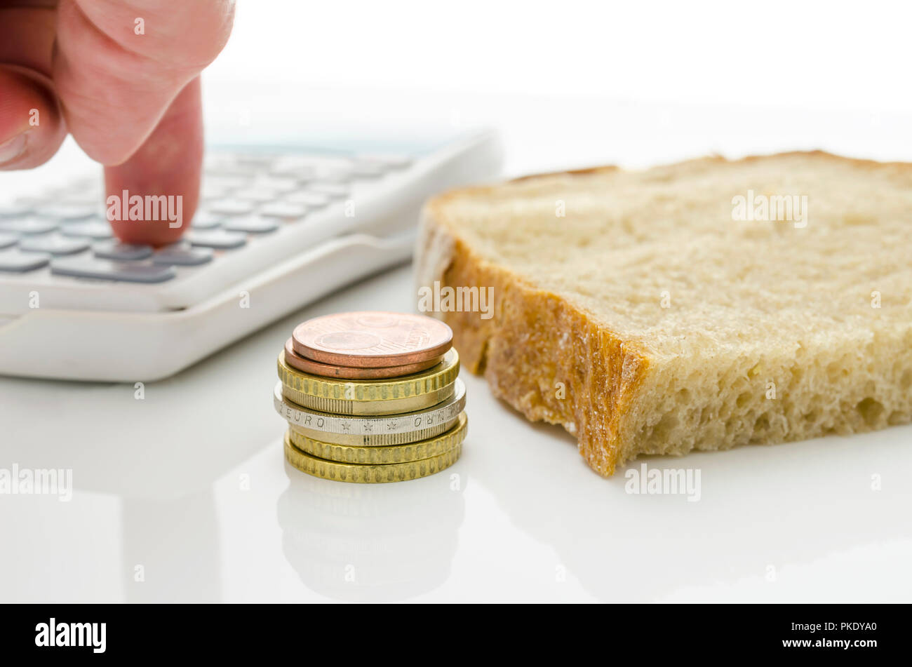 Pezzo di pane con mano maschio calcolare le spese di base. Foto Stock