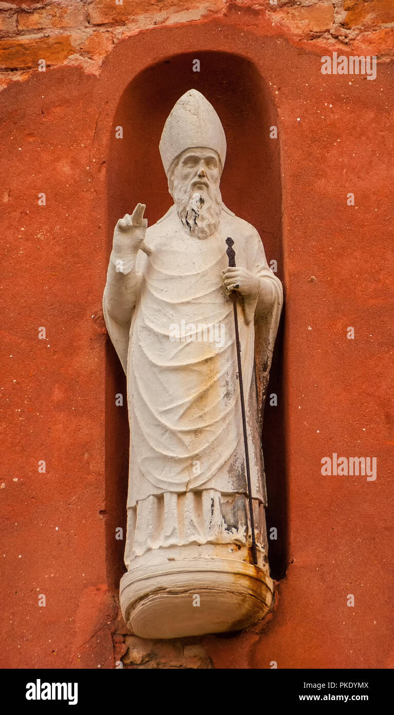 La benedizione di Papa, Vescovo o Saint con la canna da zucchero, un'antica statua su una parete nel centro storico di Venezia Foto Stock