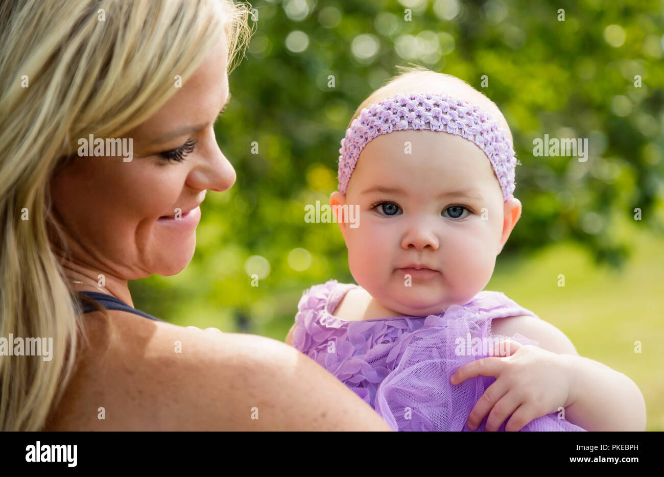 Una mamma tenendo la sua bimba mentre godendo il tempo in un parco della città nel corso di una bella cascata di pomeriggio; Edmonton, Alberta, Canada Foto Stock
