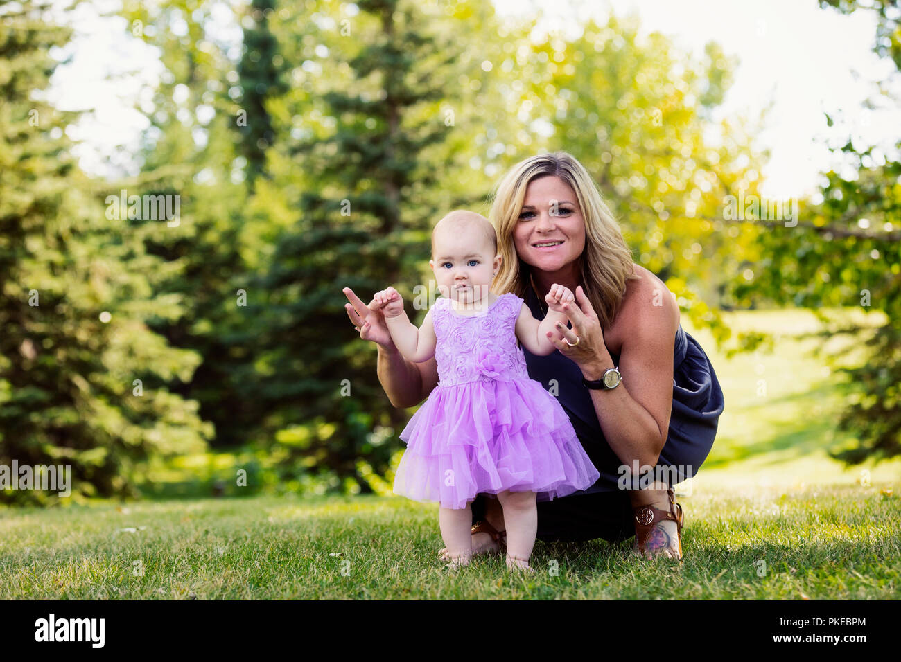 Una madre insegnare la sua bimba come andare a piedi in un parco cittadino in un caldo pomeriggio di caduta: Edmonton, Alberta, Canada Foto Stock