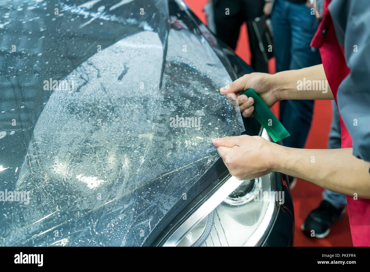 Installare lavoratore auto paint protection film con la spatola Foto Stock