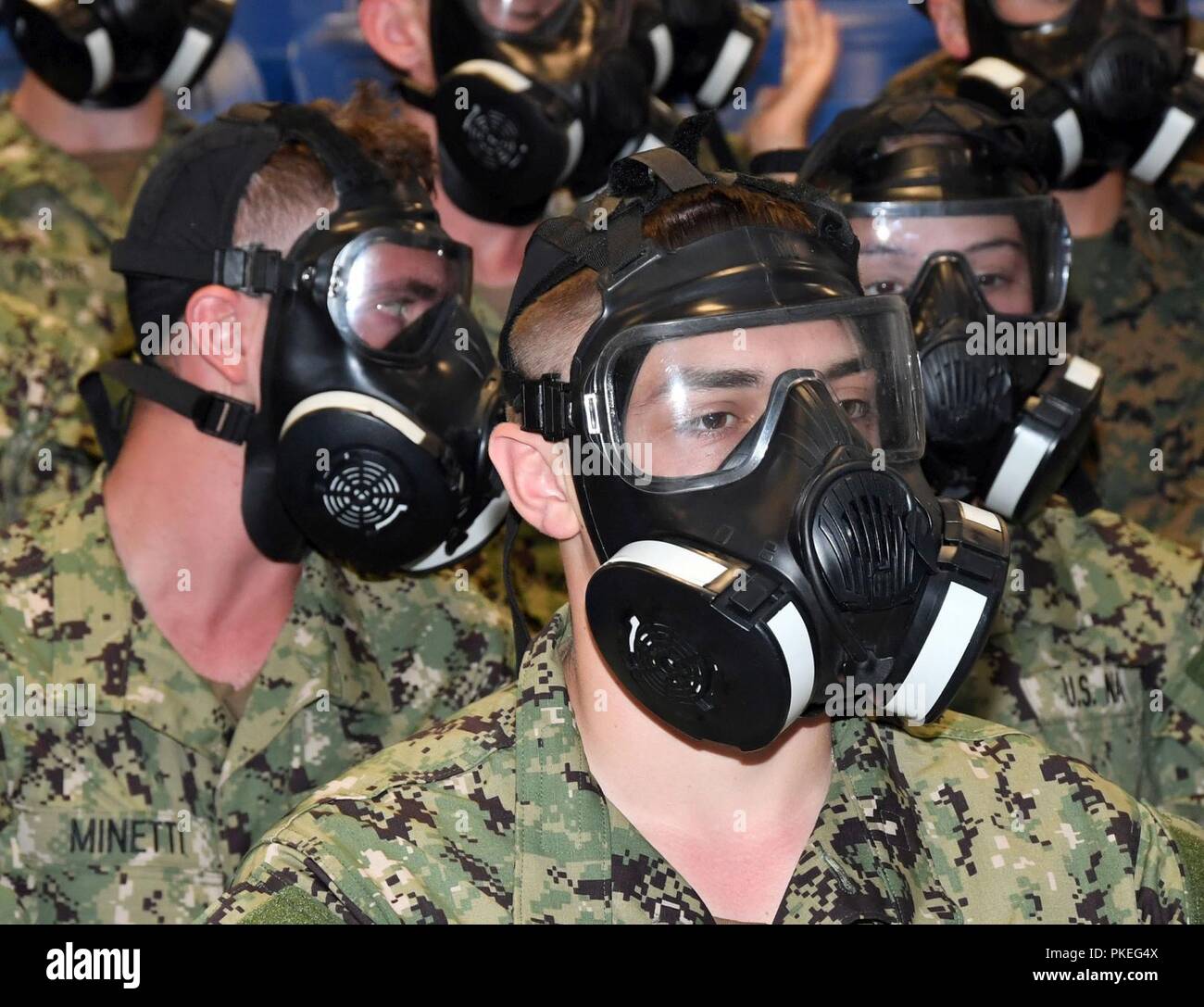 Laghi, Ill. (Luglio 27, 2018) Naval ROTC guardiamarina candidati abituarsi a indossare M50 di maschere antigas nell'USS Chief reclutare Fire Fighter Trainer ad assumere il comando di formazione (RTC). La formazione in aula la USS capo era parte della chimica, biologica e radiologici (CBR) difesa istruzione per i nuovi aspiranti guardiamarina in arrivo durante l'indottrinamento e alla marina. Più di 65 giovani uomini e donne che entrano nel loro primo anno del programma NROTC ha partecipato a due a due alla settimana programma pilota progettato per fornire standardizzato entry-level per la militarizzazione e la preparazione di aspiranti guardiamarina con un comune orientamento di formazione. Foto Stock