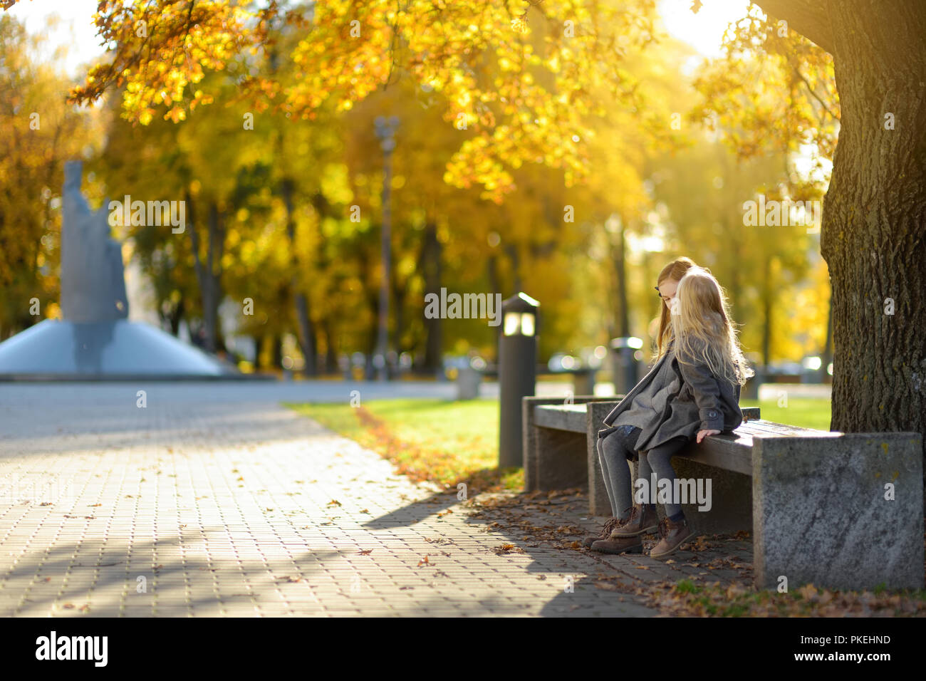 Due graziosi bambine divertirsi sulla bellissima giornata autunnale. Felici i bambini che giocano nel parco d'autunno. Bambini raccolta giallo caduta delle foglie. Attività di autunno Foto Stock