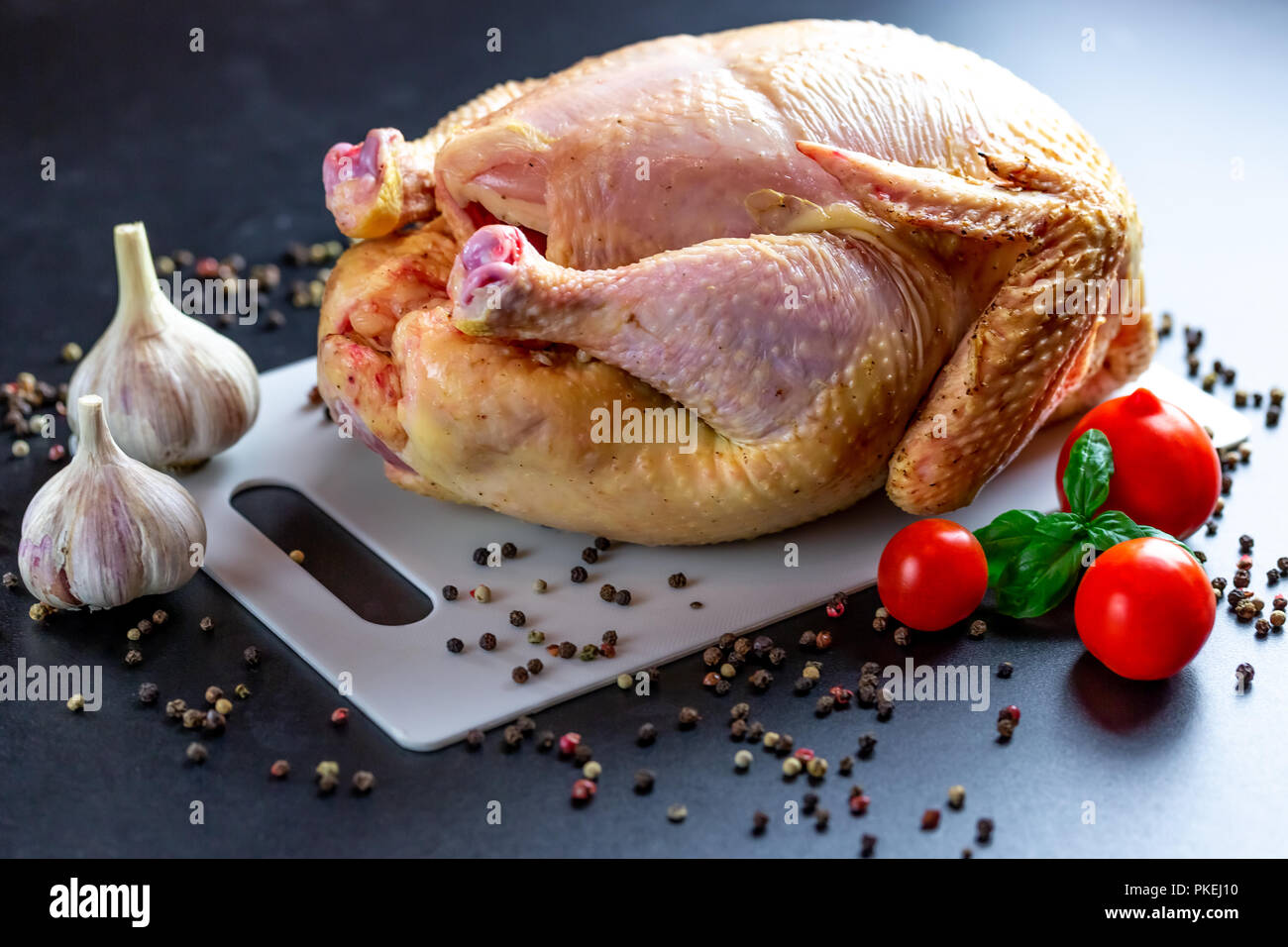 Pollo con spezie e verdure al buio su un tavolo. Preparazione per il giorno del ringraziamento. Sfondo di natale Foto Stock