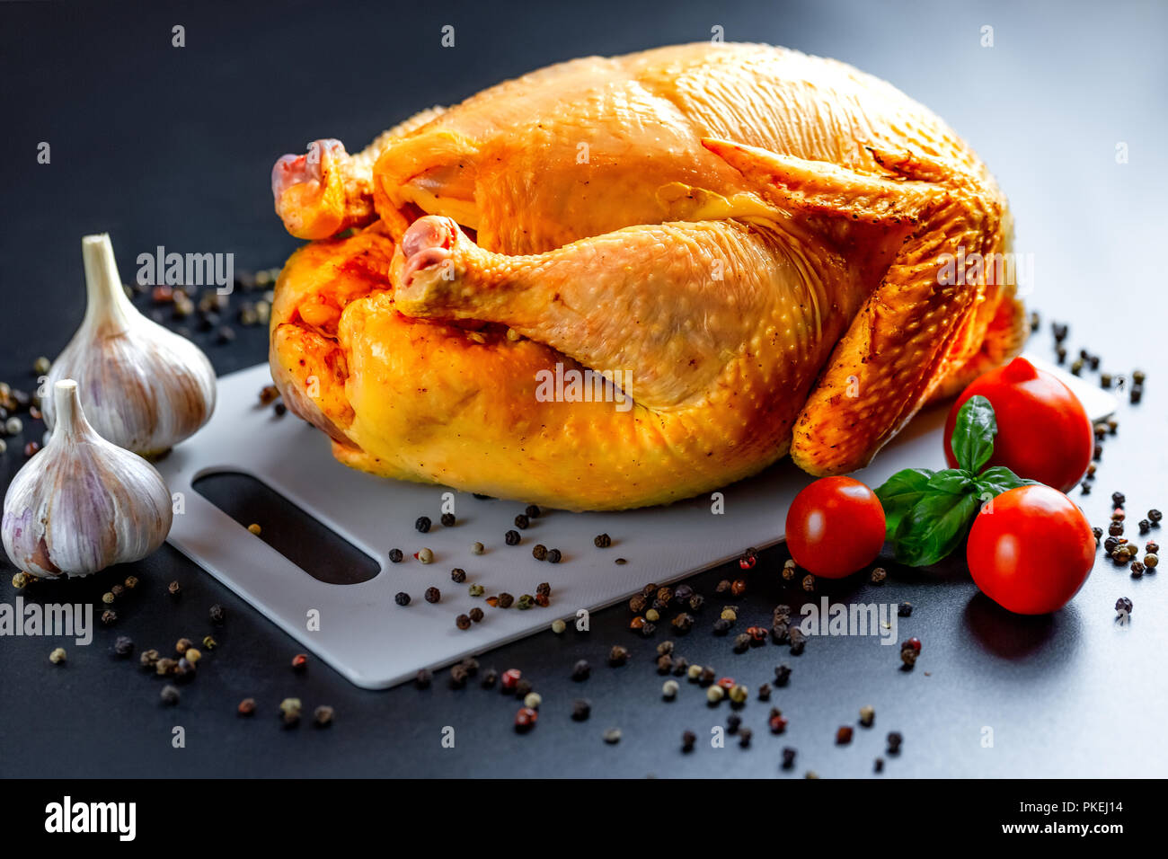Pollo con spezie e verdure al buio su un tavolo. Preparazione per il giorno del ringraziamento. Sfondo di natale Foto Stock