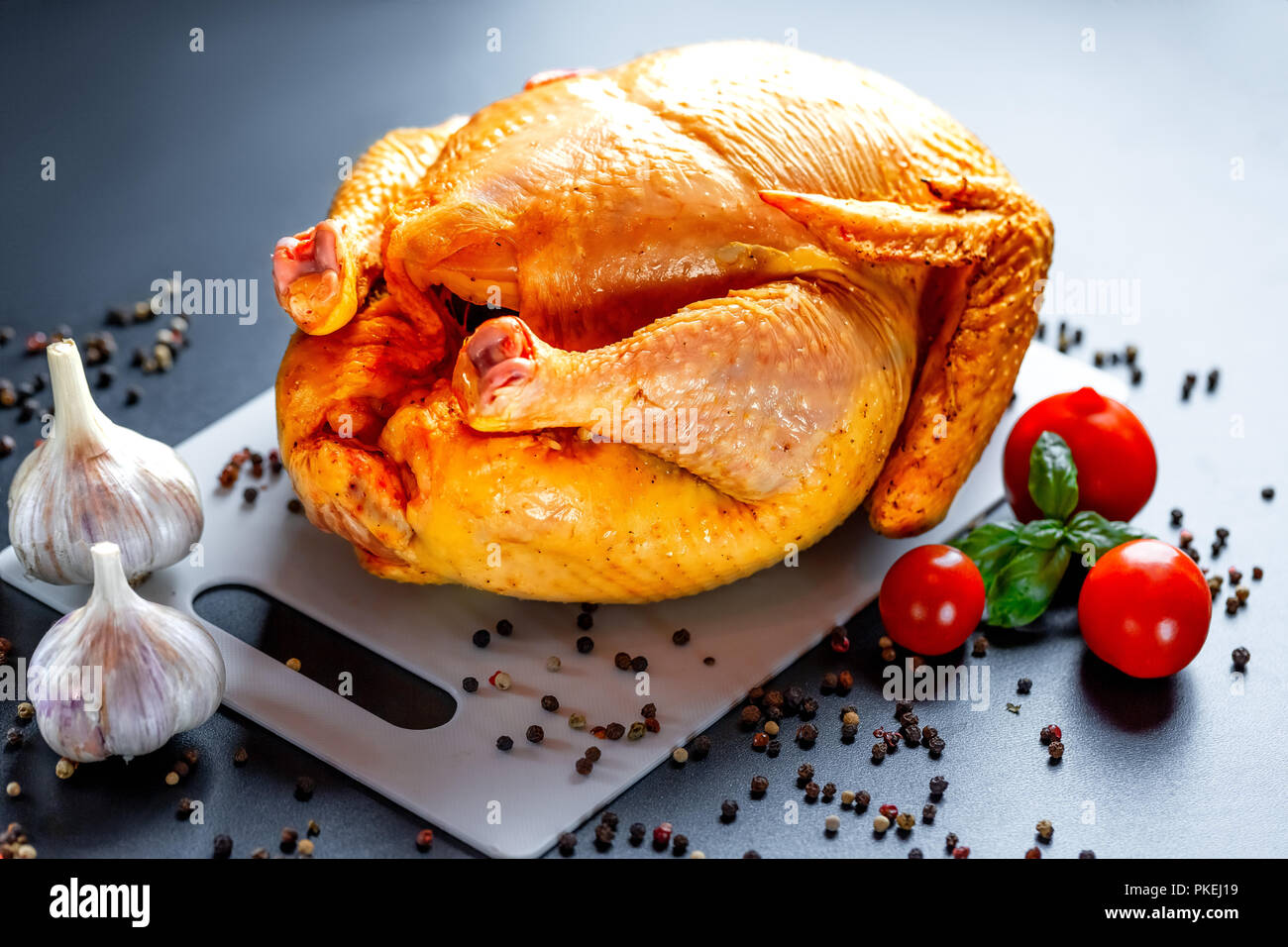 Pollo con spezie e verdure al buio su un tavolo. Preparazione per il giorno del ringraziamento. Sfondo di natale Foto Stock
