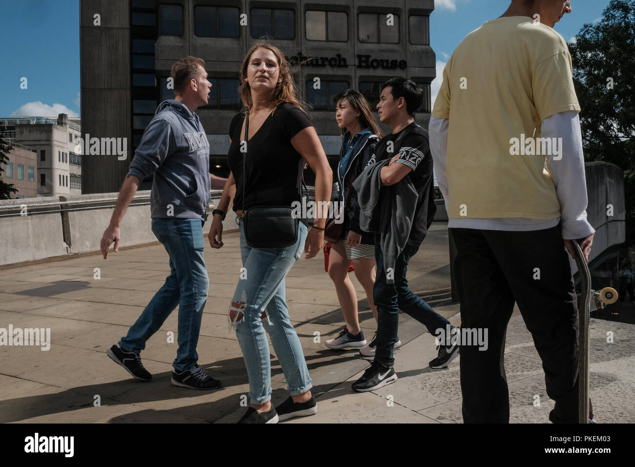 La gente che passa tra di loro in una giornata di sole sul Ponte di Londra, Regno Unito Foto Stock