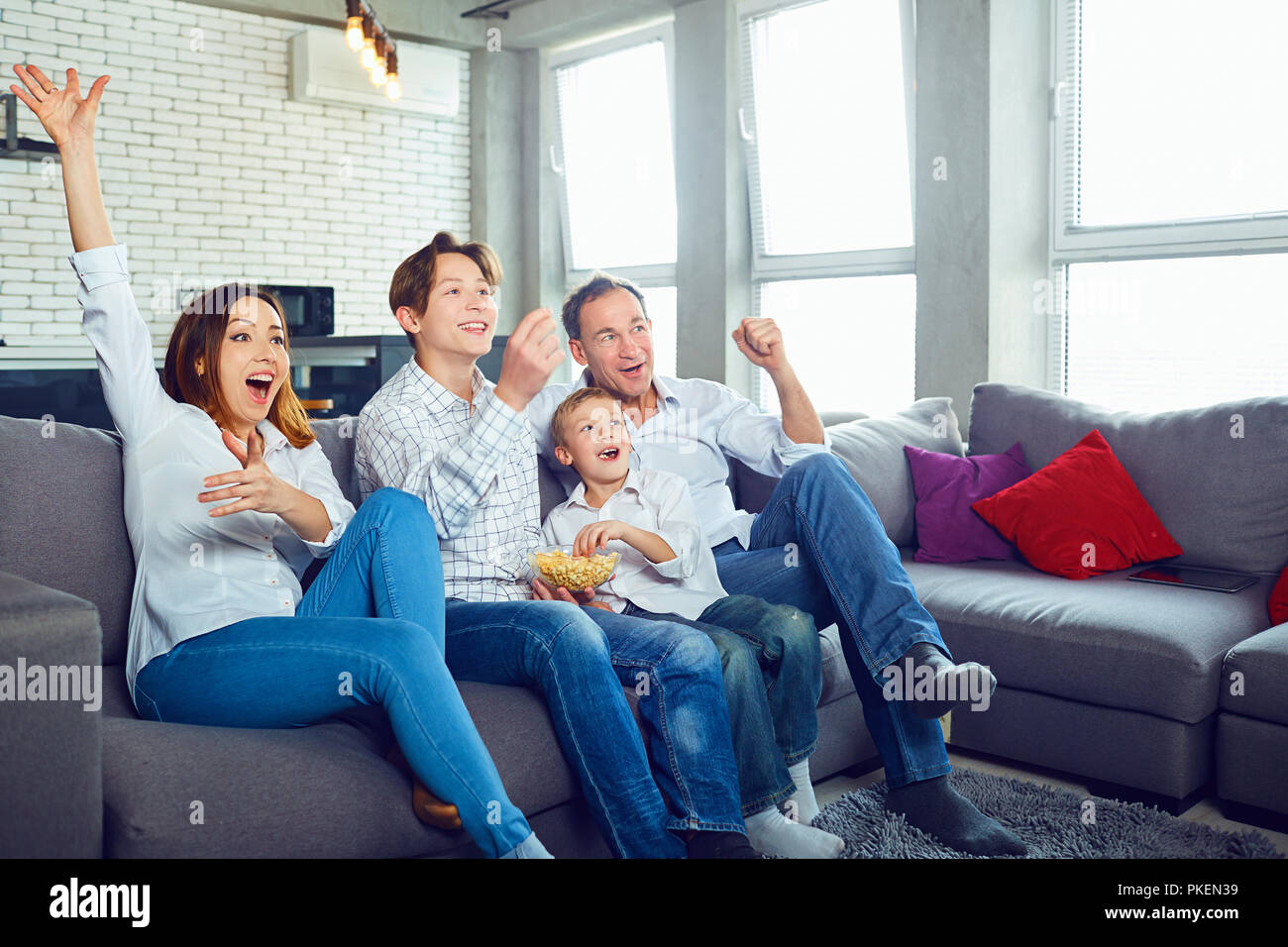 La famiglia felice divertirsi guardando la TV SEDUTA. Foto Stock