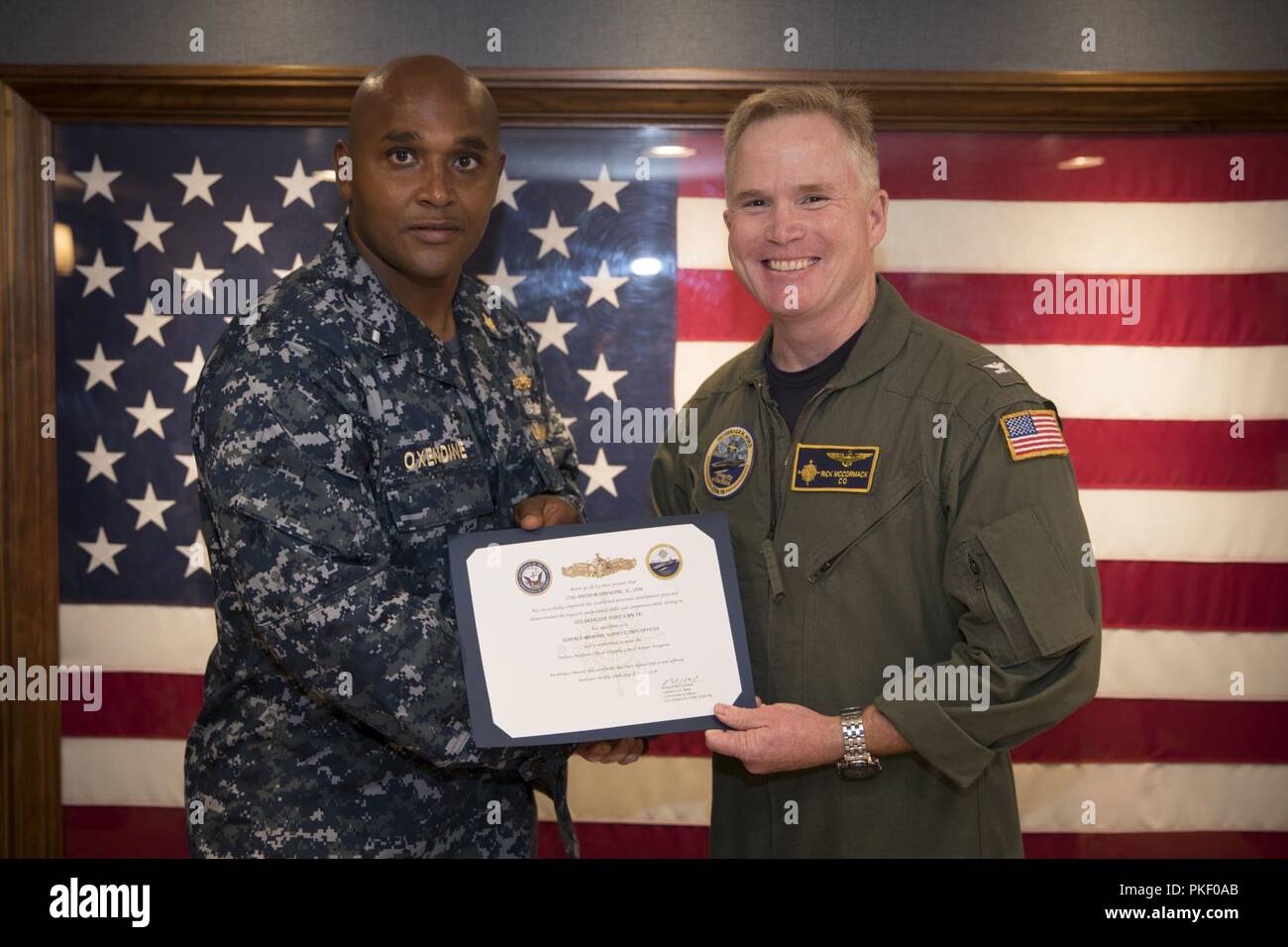 NEWPORT NEWS, Va. (Agosto 3, 2018) Il tenente j.g. Anrdew Oxendine, da New Bern, North Carolina, assegnato alla USS Gerald Ford (CVN 78) il reparto di approvvigionamento riceve la sua superficie di alimentazione Warfare Corps Officer certificato da Capt. Richard McCormack, Ford comandante. Foto Stock