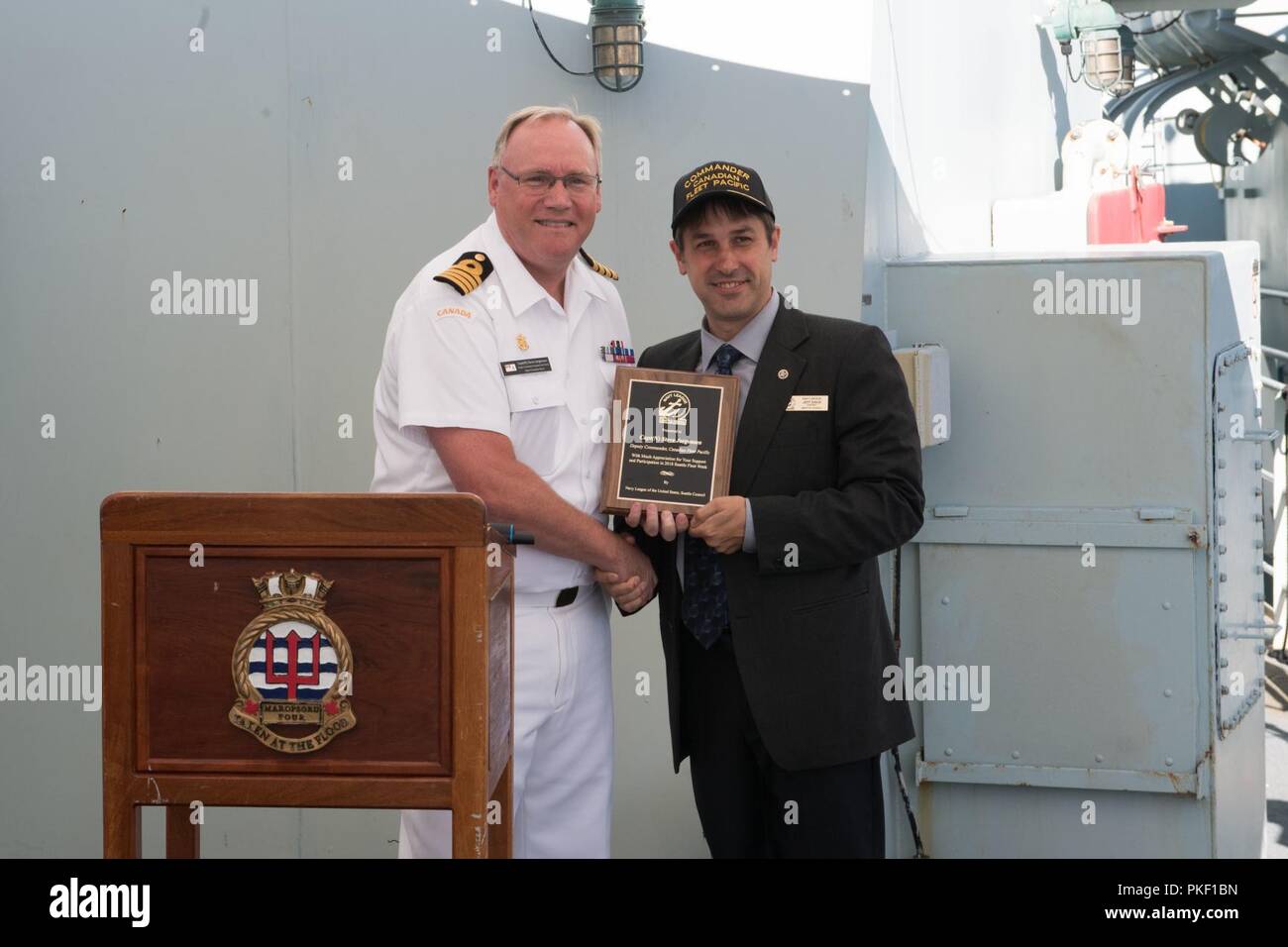 SEATTLE (4 agosto 2018) Capt. Steve Jorgensen, vice comandante della flotta Canadese Pacific, riceve una placca da Seattle Navy League Presidente Jeff Davis durante un ricevimento detenute a bordo di Kingston-classe di difesa costiera navi HMCS Whitehorse (710) e HMCS Yellowknife (706) durante la Seattle flotta Seafair settimana. Seafair Settimana della flotta è una celebrazione annuale del mare servizi in cui i marinai, Marines e Guardia Costiera di membri da visitare U.S. La marina e la Guardia costiera navi e navi da Canada rendono la città una porta di chiamata. Foto Stock