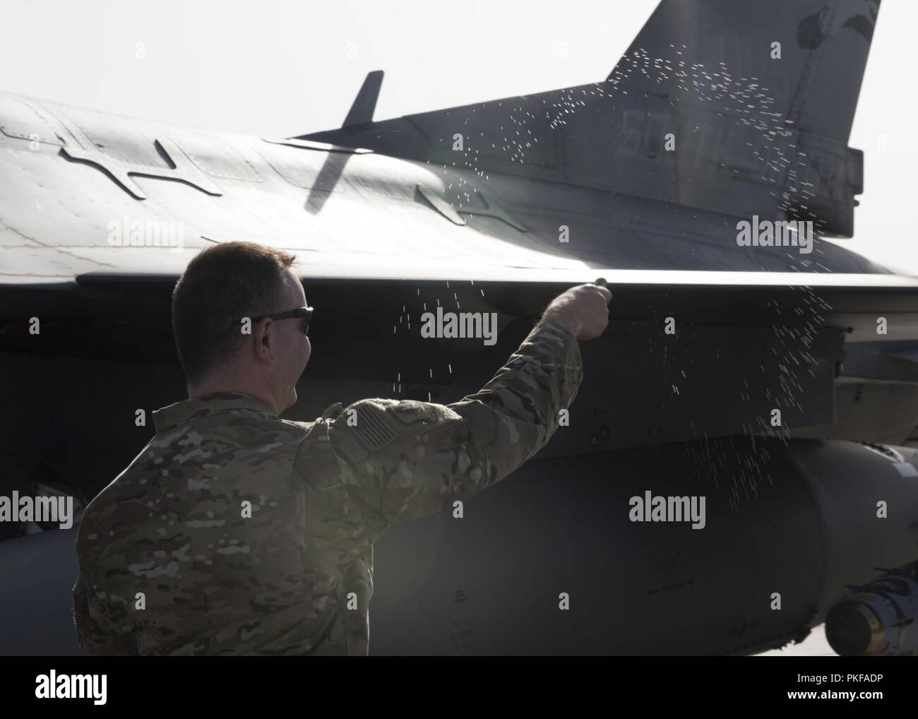 Stati Uniti Air Force Capt. Dariusz Barna, cappellano, getta acqua santa con un aspergillum su di un F-16 Fighting Falcon a 455th Air Expeditionary Wing (AEW), Bagram Airfield, Afghanistan, 10 agosto 2018, durante una cerimonia religiosa sulla rampa di aeromobili. L'evento è stato ospitato dal 455th AEW Cappellani Corps che sono incaricati di fornire cura pastorale ministero e counseling a quelle di fede e di quelle di nessuna fede mentre assegnato alla 455th AEW. Foto Stock