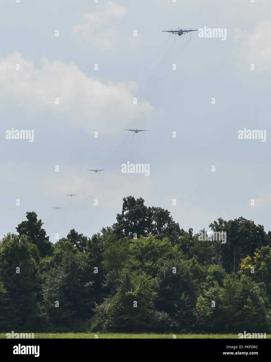 Cinque C-130H Hercules emerge al di sopra della linea di albero a Camp Ravenna la zona di rilascio il 10 agosto 2018. Youngstown riserva d'aria stazione Tac ospitato settimana sono state C-130s dall'anno, Dobbins Air Aggregato soggetto a riserva e Maxwell Air Force Base hanno gareggiato in una serie di sfide per la formazione. L'ultima settimana di Tac sfida era una nave sei tactical airdrop sfida per vedere che C-130 potrebbe ottenere il suo effettivo pesante o ad alta velocità di erogazione del contenitore System airdrop più vicino al punto di impatto. Foto Stock