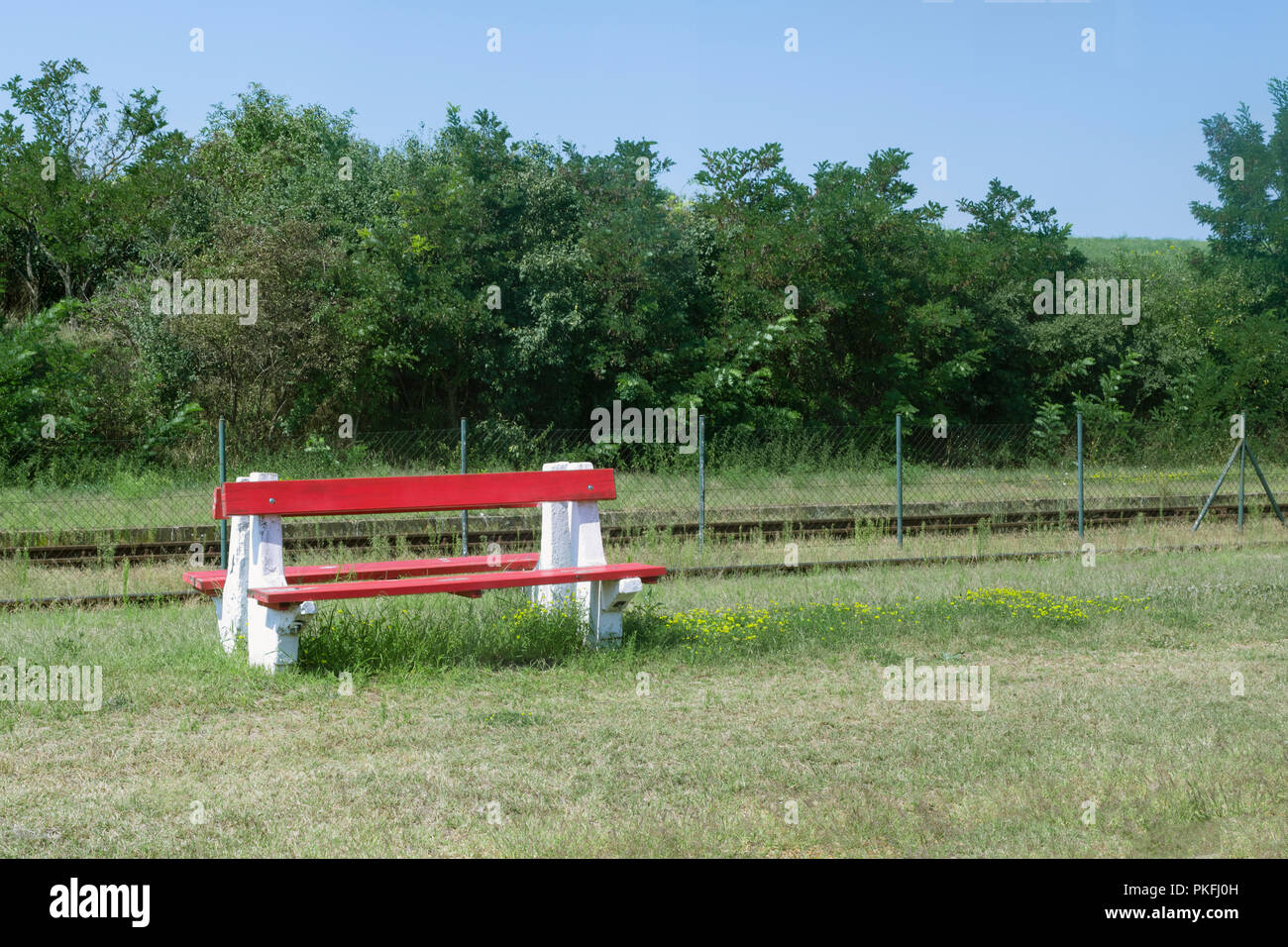 Banco di rosso e fiori di colore giallo in corrispondenza di una zona rurale stazione ferroviaria in Europa orientale, Ungheria Foto Stock