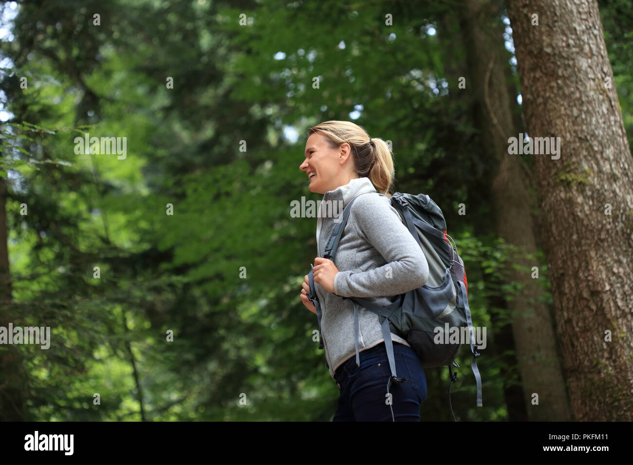 Una donna felice escursionismo in una foresta Foto Stock