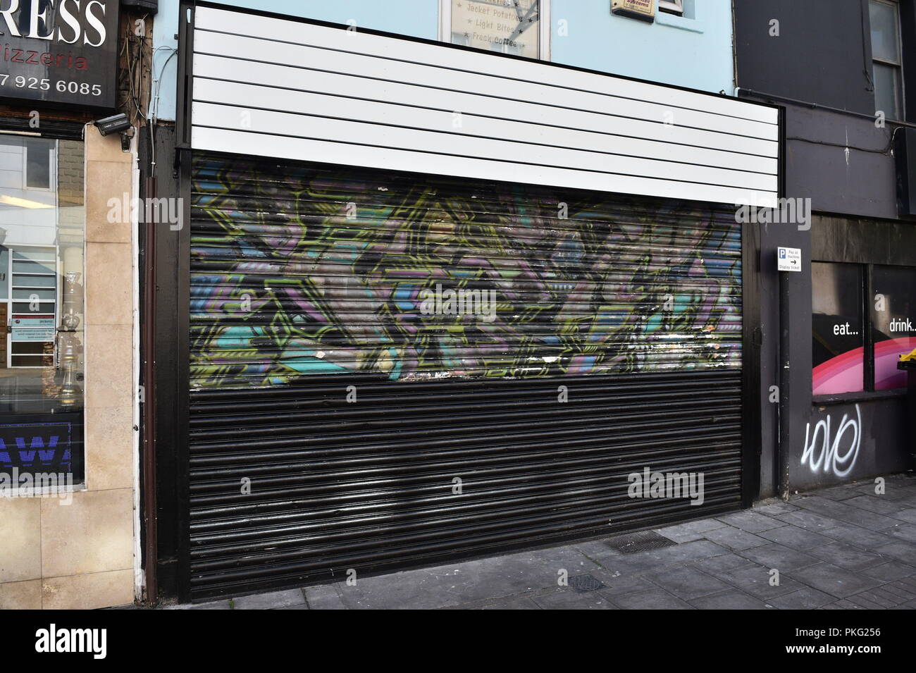 Un Banksy murale sulla shopfront tapparelle su Park Row, Bristol è stata accidentalmente dipinte in bianco e nero dai nuovi proprietari del negozio durante i lavori di ristrutturazione. Foto Stock
