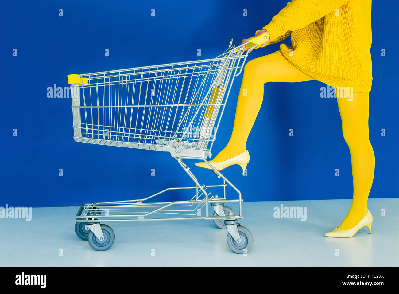 Vista ritagliata della donna appoggiata sul carrello su sfondo blu Foto Stock