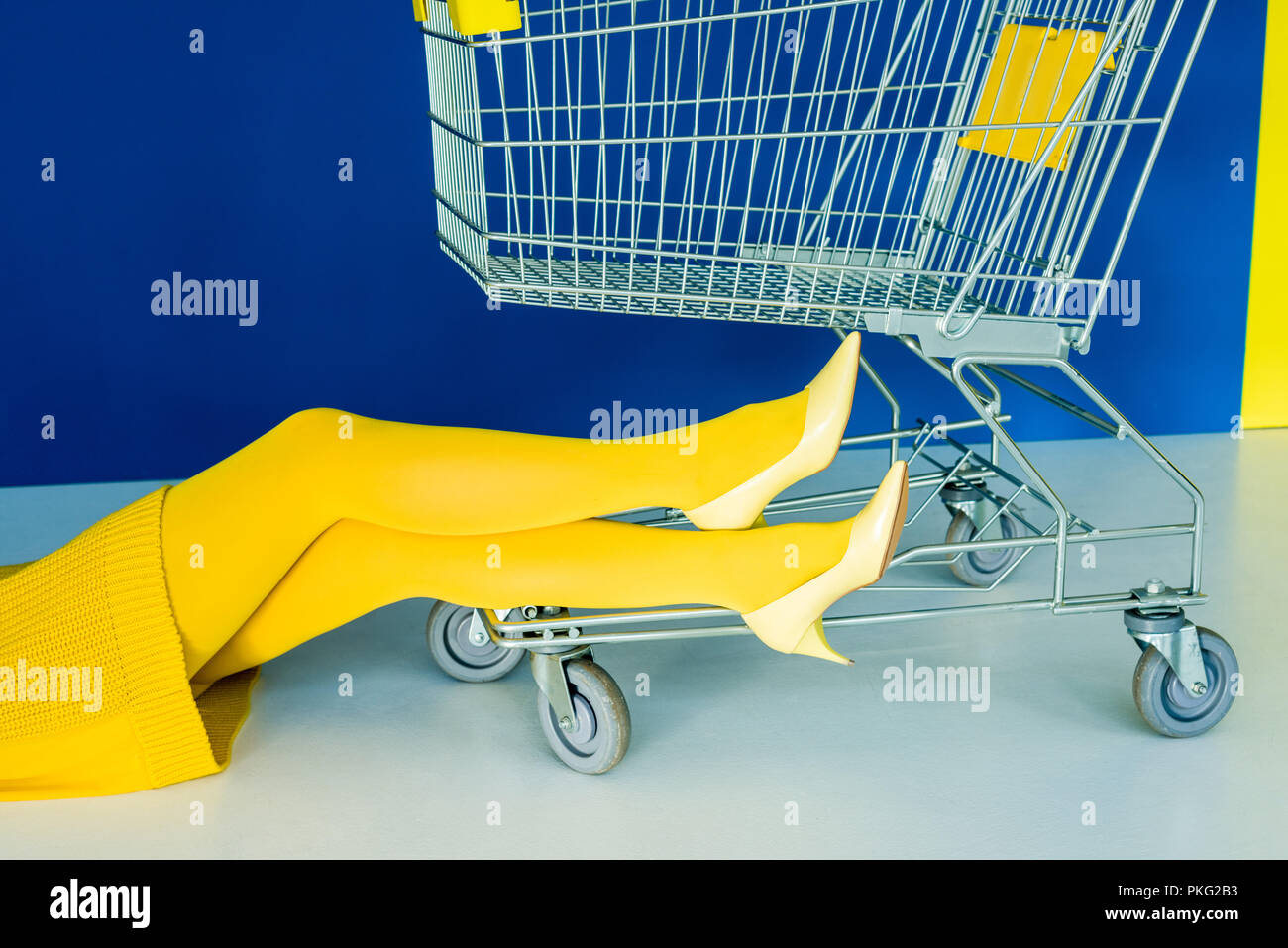 Vista ritagliata della gambe femmina in giallo le scarpe di carrello su sfondo blu Foto Stock