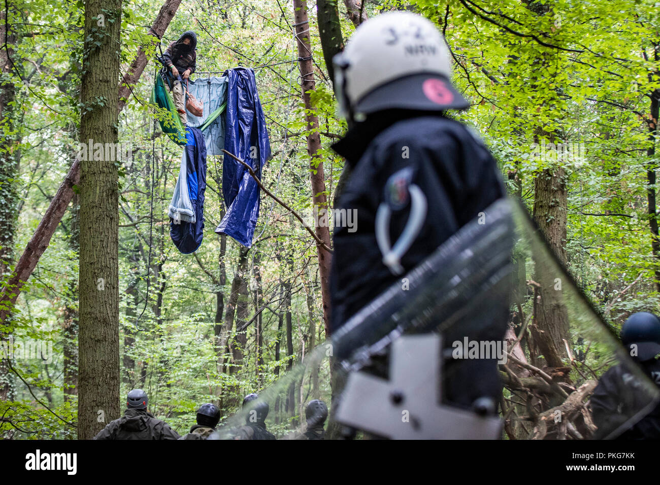 13 settembre 2018, della Renania settentrionale-Vestfalia, Morschenich: 13 settembre 2018, Germania, Morschenich: gli agenti di polizia sono in piedi di fronte ad una barricata in cui un attivista ha legato se stessa verso il basso. Con una massiccia presenza di polizia, autorità della lignite area mineraria di Hambach foresta hanno iniziato a cancellare la attivisti ambientali' barricate. Foto: Marcel Kusch/dpa Foto Stock