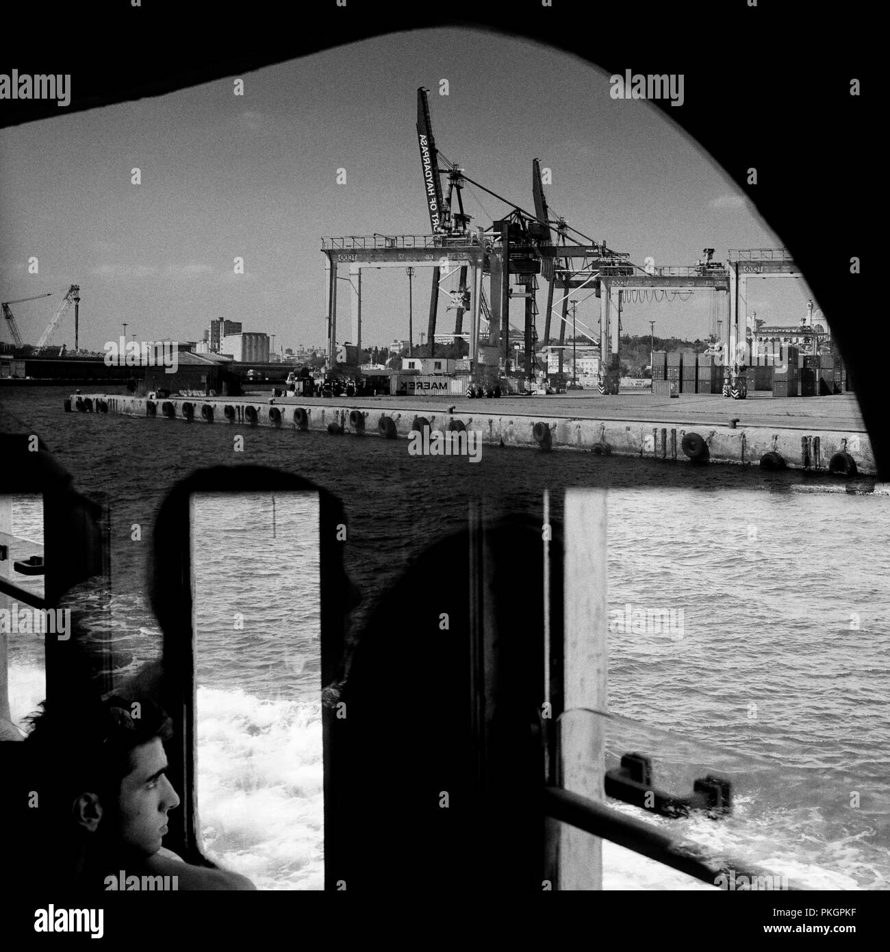 Istanbul, Turchia - 25 agosto 2018: un giovane uomo guarda la vista del porto di Haydarpasa. Ci sono delle belle riflessioni sulla finestra. Foto Stock