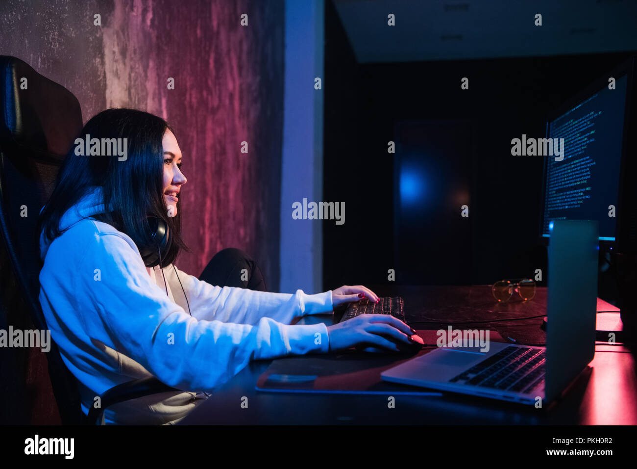 Allegro giovane donna freelancer in abbigliamento casual digitando il codice di programmazione lavoro sul laptop moderno computer a casa. Studente positivo aggiornamento software su netbook Foto Stock