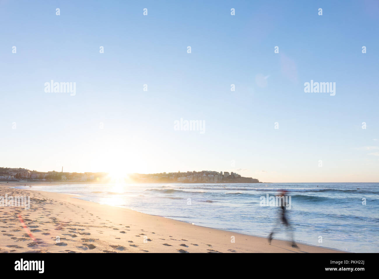La spiaggia di Bondi, Sydney, Australia - un pareggiatore corre lungo la spiaggia di sunrise Foto Stock
