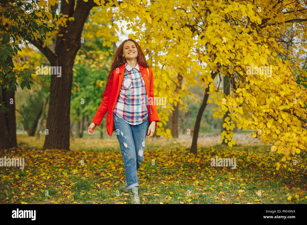 Felice ragazza con lunghi capelli ondulati godendo di Autunno nel parco. Bella giovane donna di trascorrere del tempo in autunno park. Foto Stock