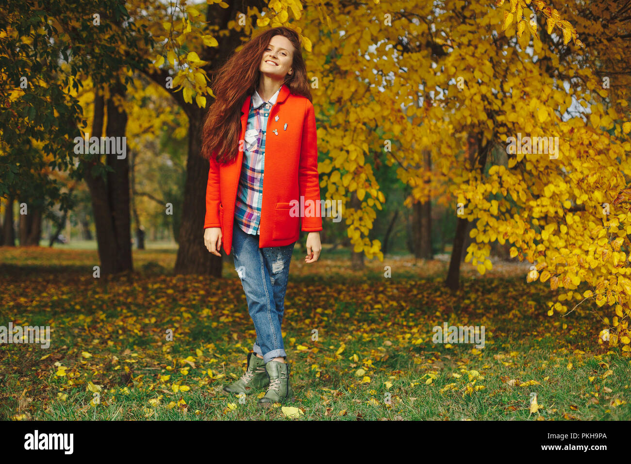 Felice ragazza con lunghi capelli ondulati godendo di Autunno nel parco. Bella giovane donna di trascorrere del tempo in autunno park. Foto Stock