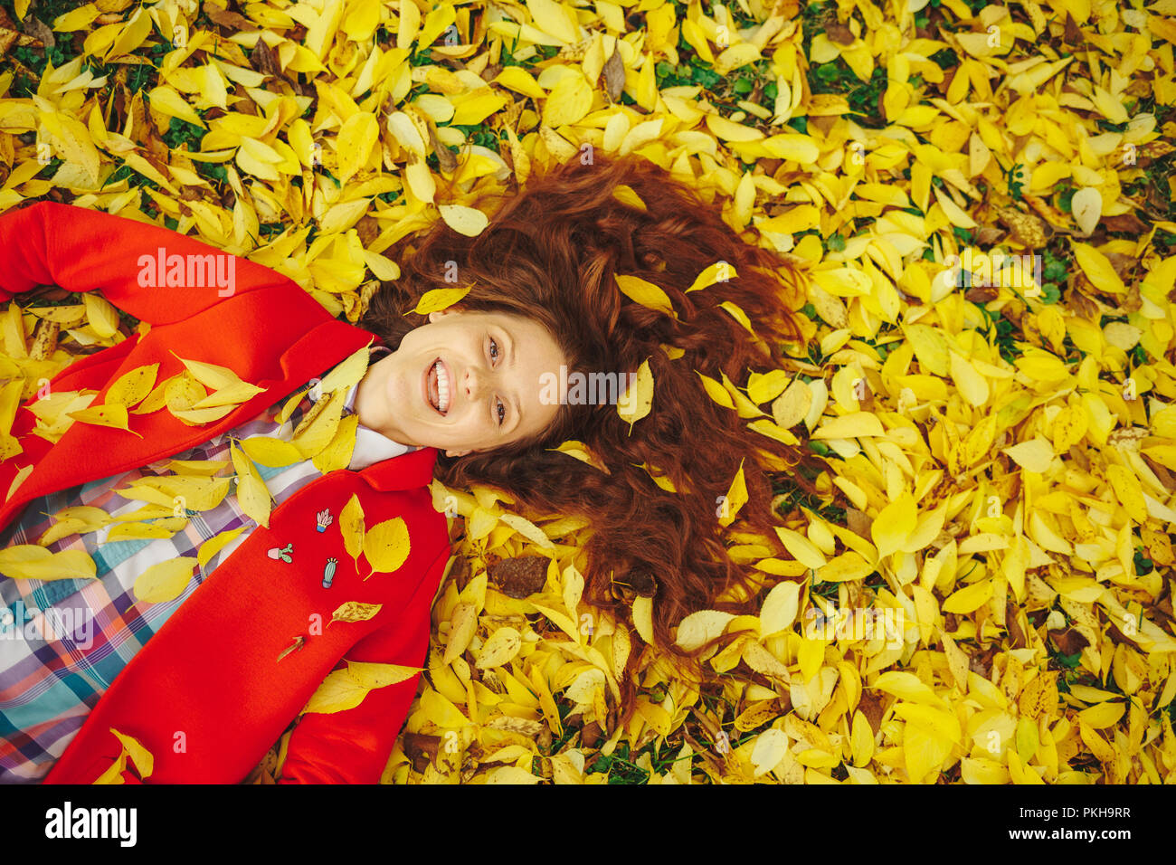 In autunno le foglie che cadono sulla felice giovane donna nella foresta. Bella ragazza felice che stabilisce in giallo le foglie di autunno. Foto Stock