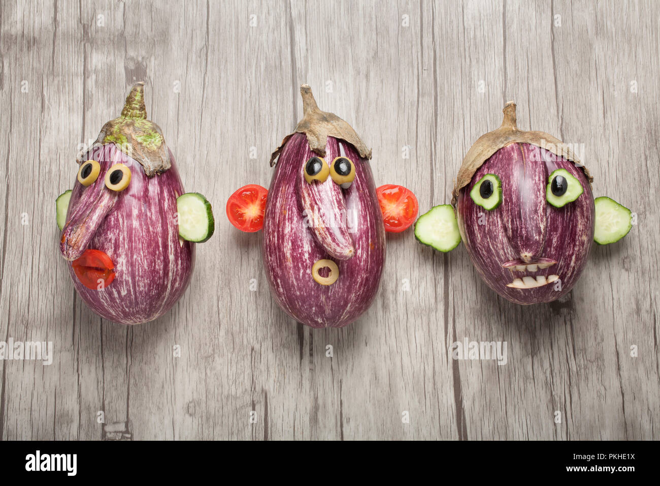 Tre facce di melanzane con sul pannello di legno Foto Stock