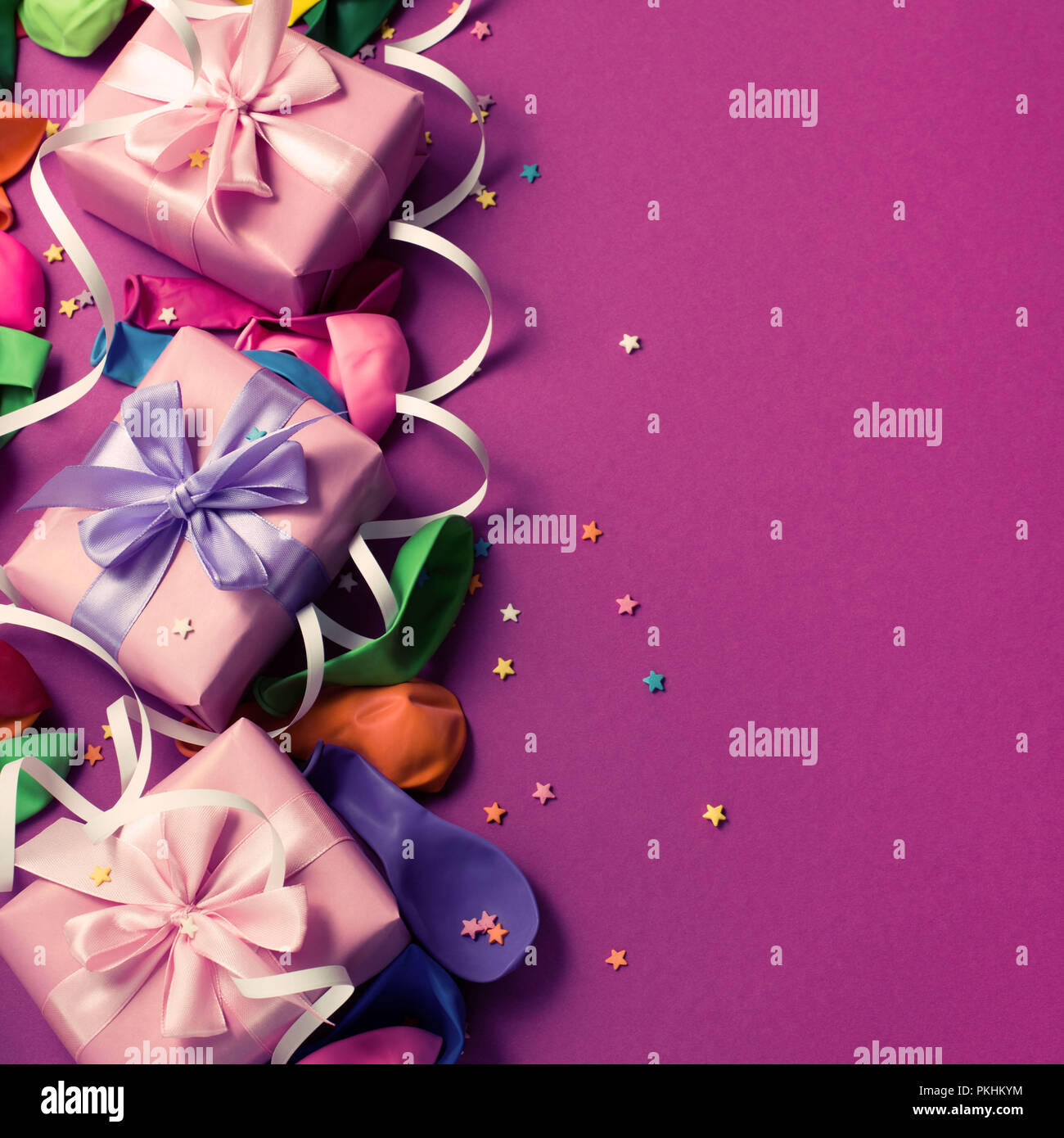 Sfondo di festa del materiale viola palloncini colorati streamers coriandoli tre scatole dono. Vista superiore piatta copia laici tonificante dello spazio Foto Stock