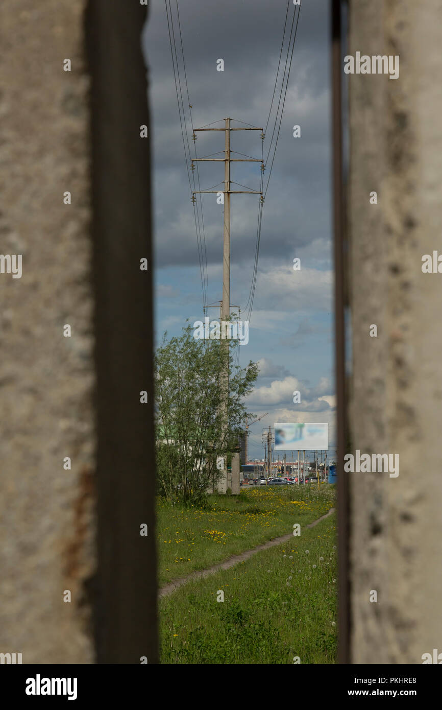 Un close-up di due poli tra i quali vi è una linea di alimentazione con fili isolanti e colonne di cemento in città Foto Stock